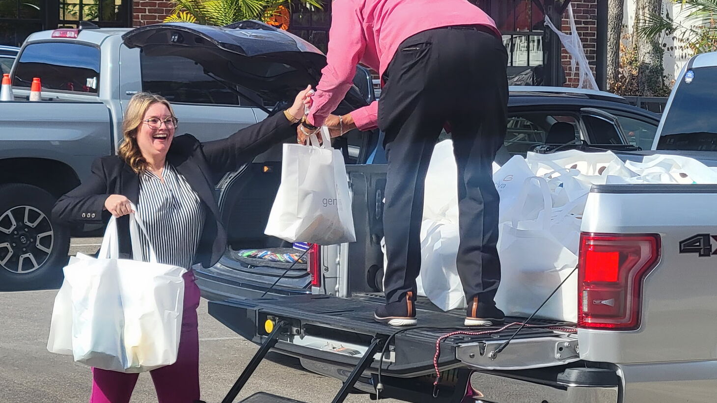 Morgan Angles handing bags to someone standing in the bed of a truck