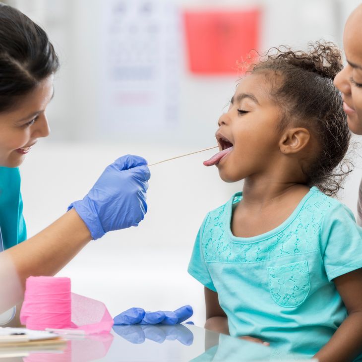 Female nurse looking in child's mouth.