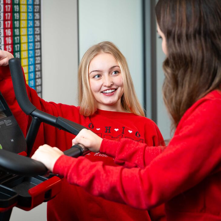 young woman coaching another young woman on a treadmill