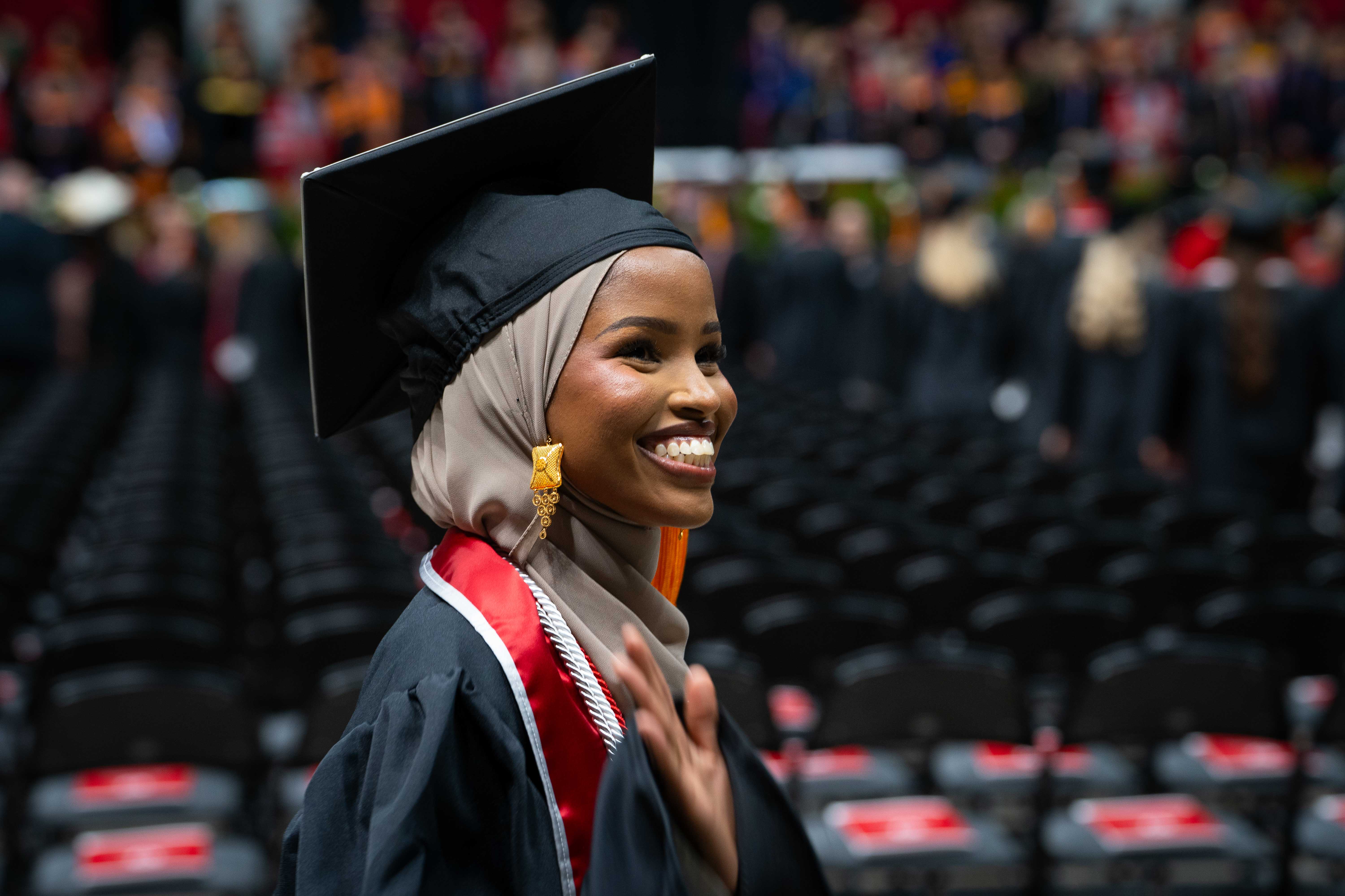 nursing student in graduation regalia waving to family at Convocation ceremony