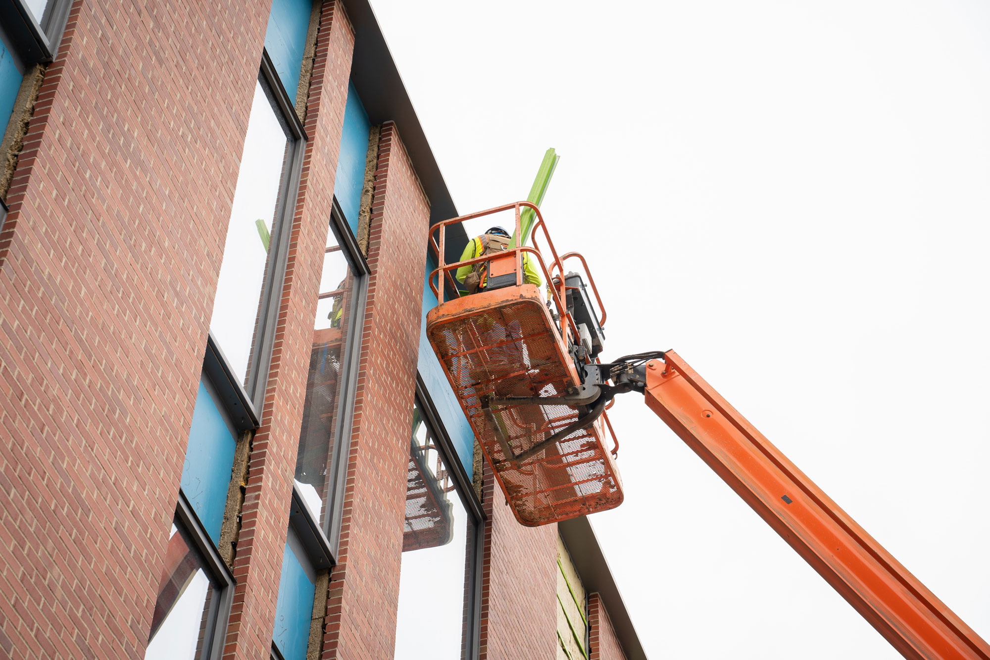photo of person in crane working on brick exterior of Jane E. Heminger hall
