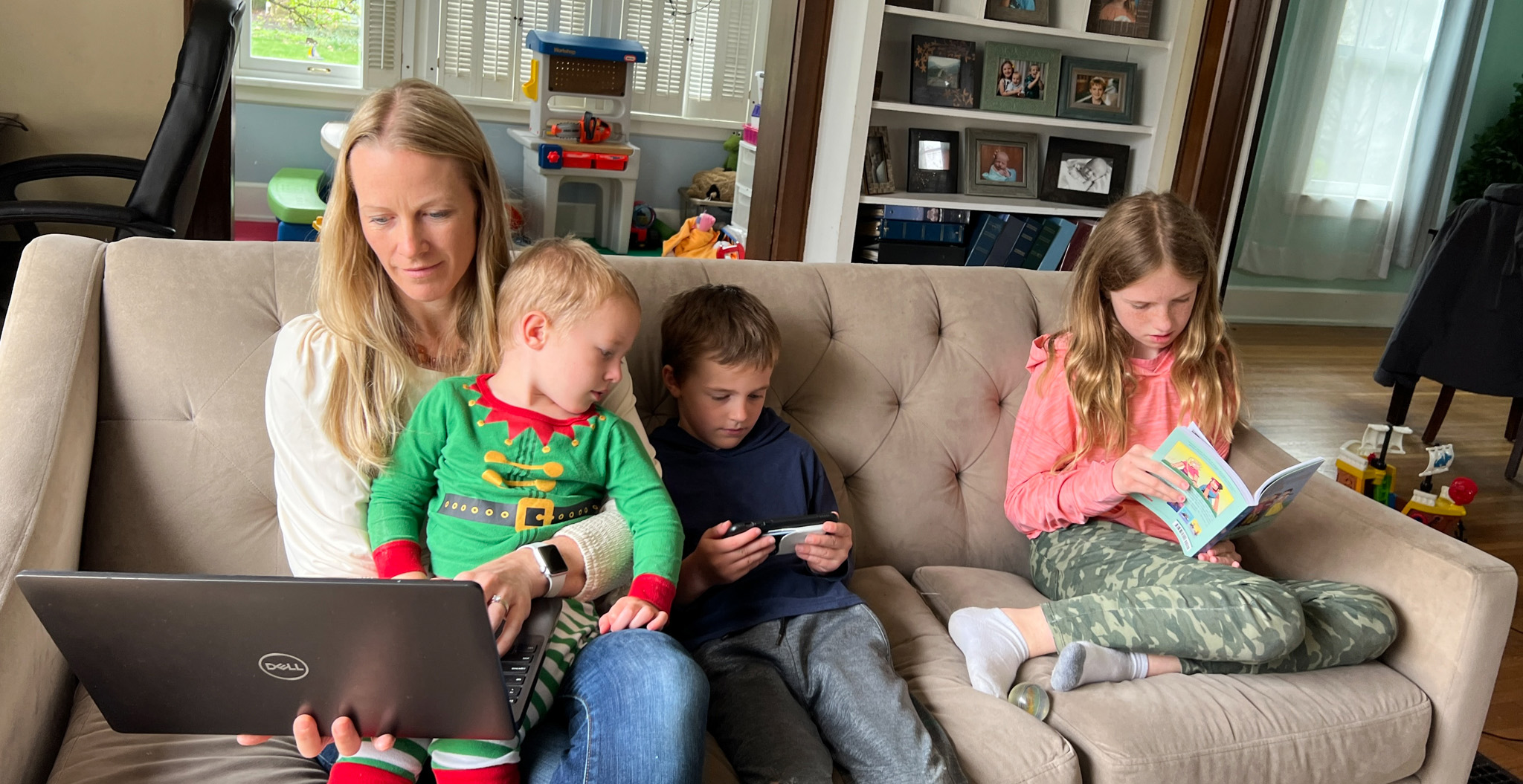 Kate Gawlik working on her laptop and holding her kids