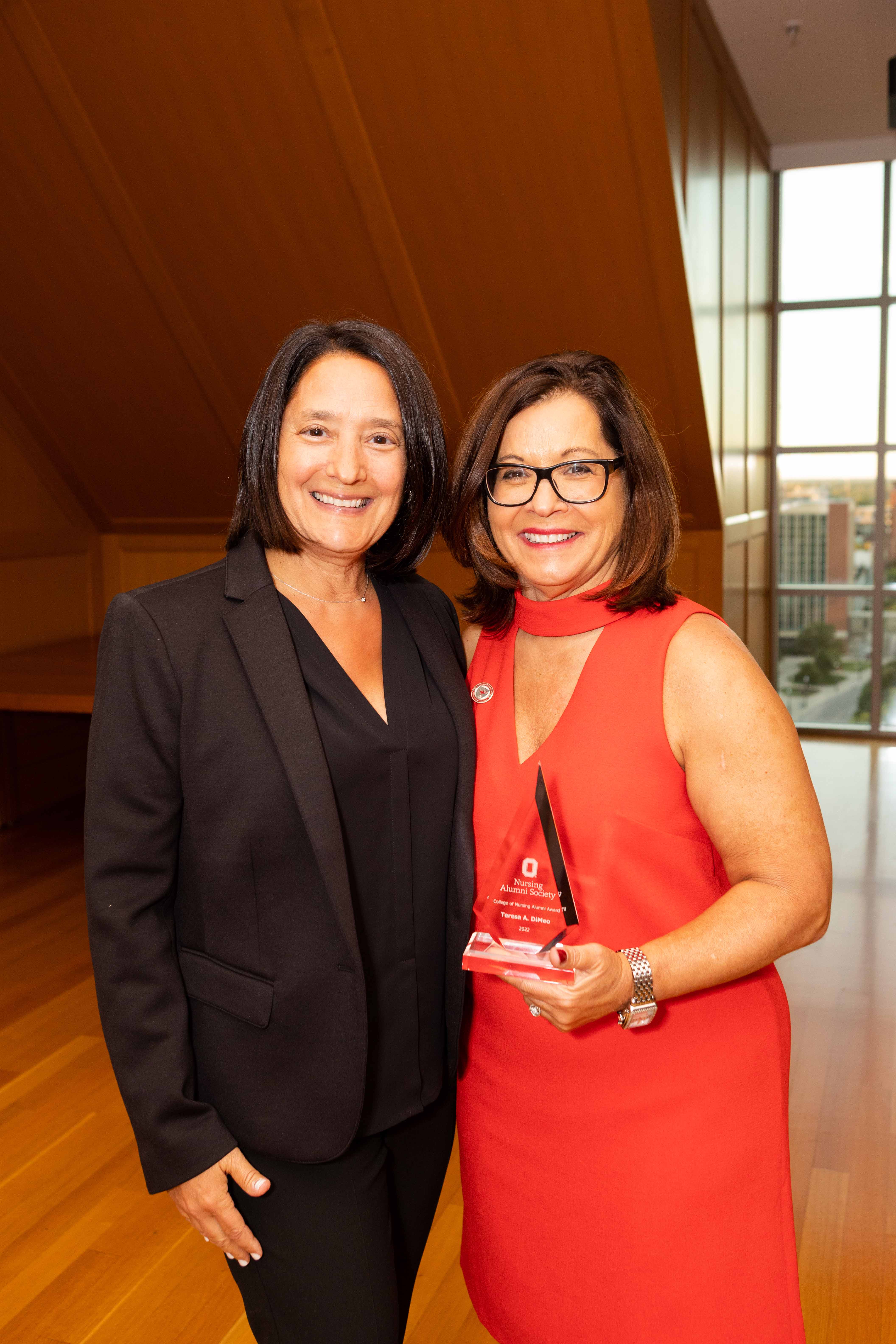 Teresa DiMeo receiving the College of Nursing Alumni Award, 2022, with support from her sister, Annmarie DiMeo