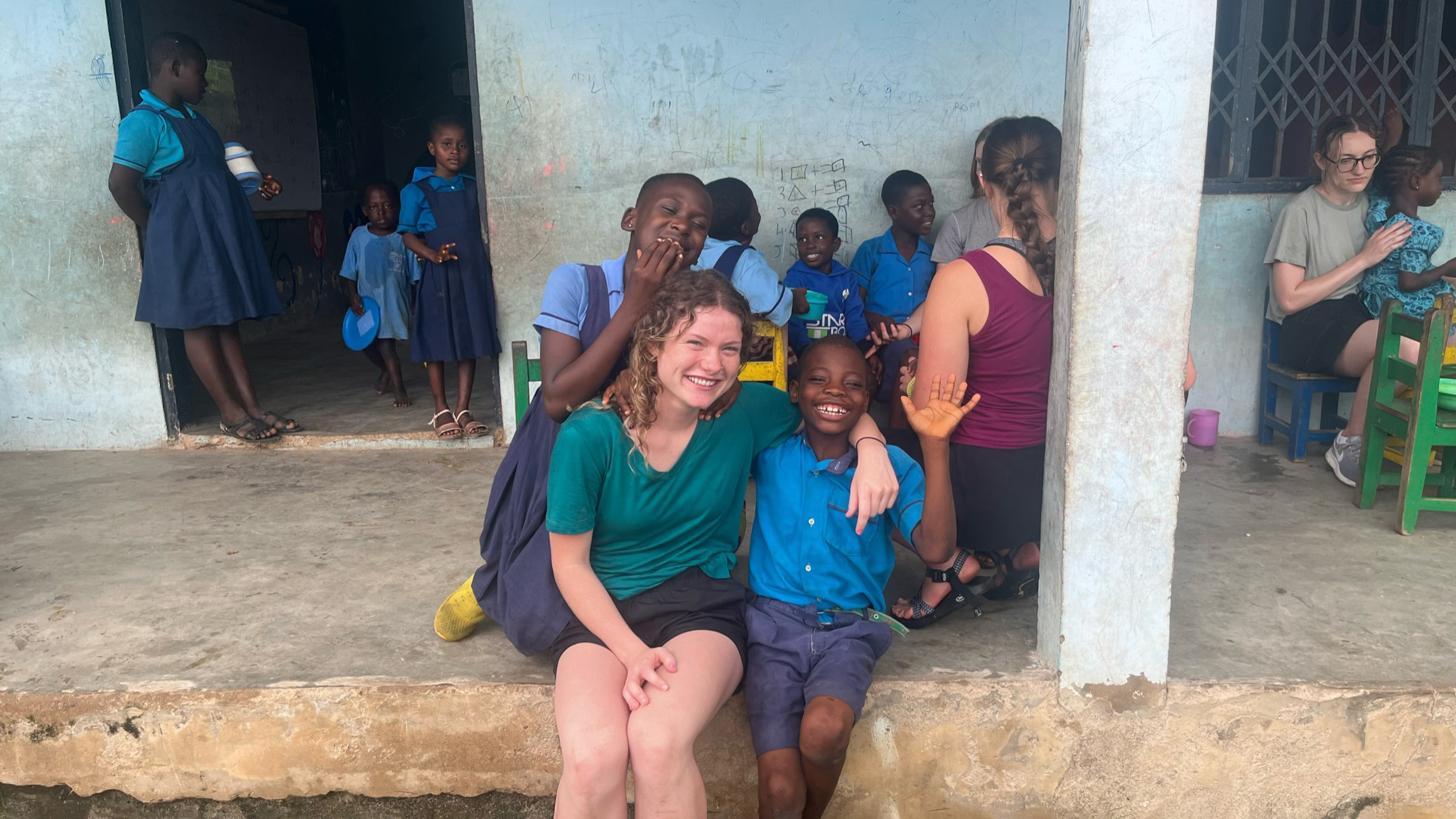 student volunteer poses with children outside orphanage