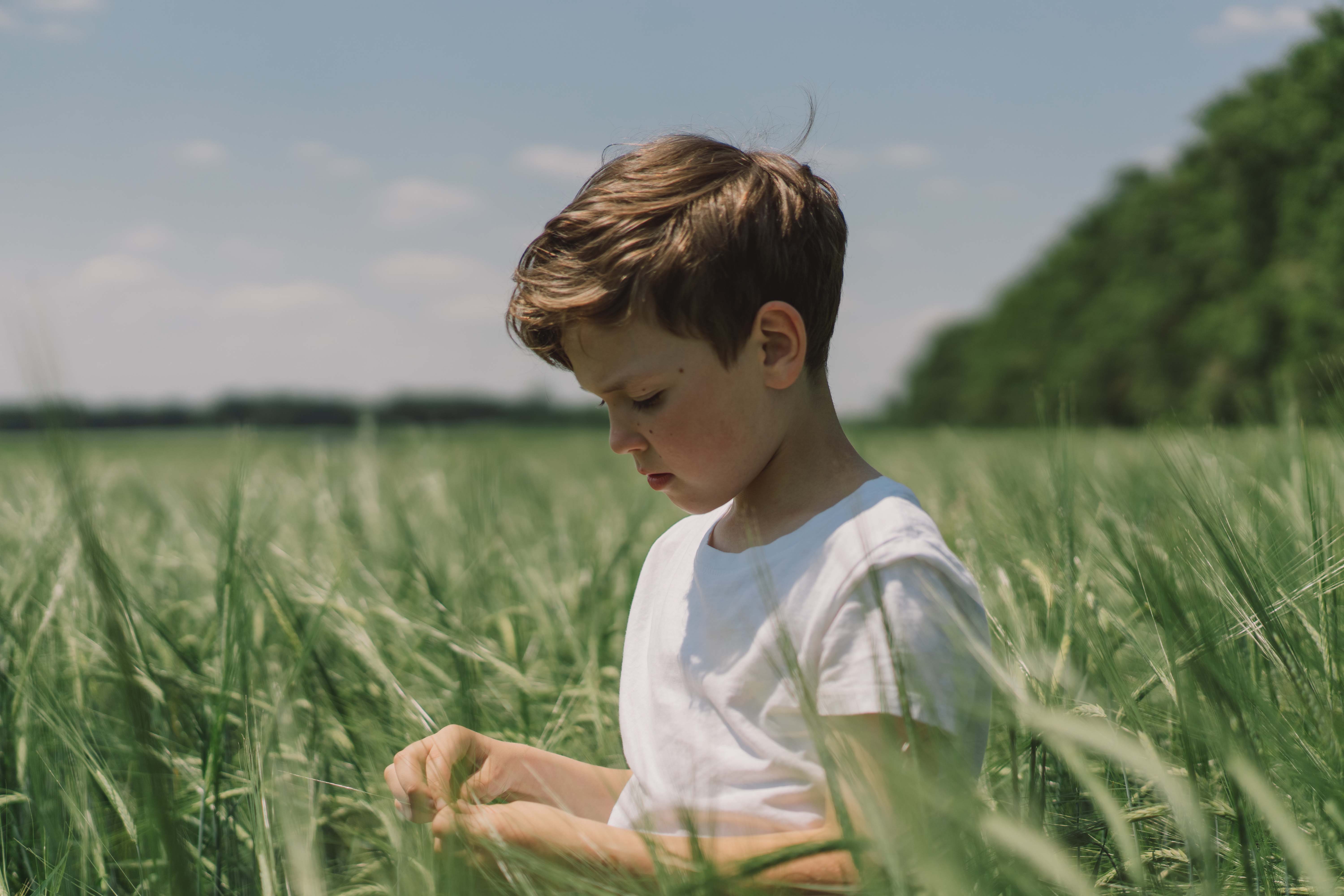 Young boy in white t-shirt standing in field