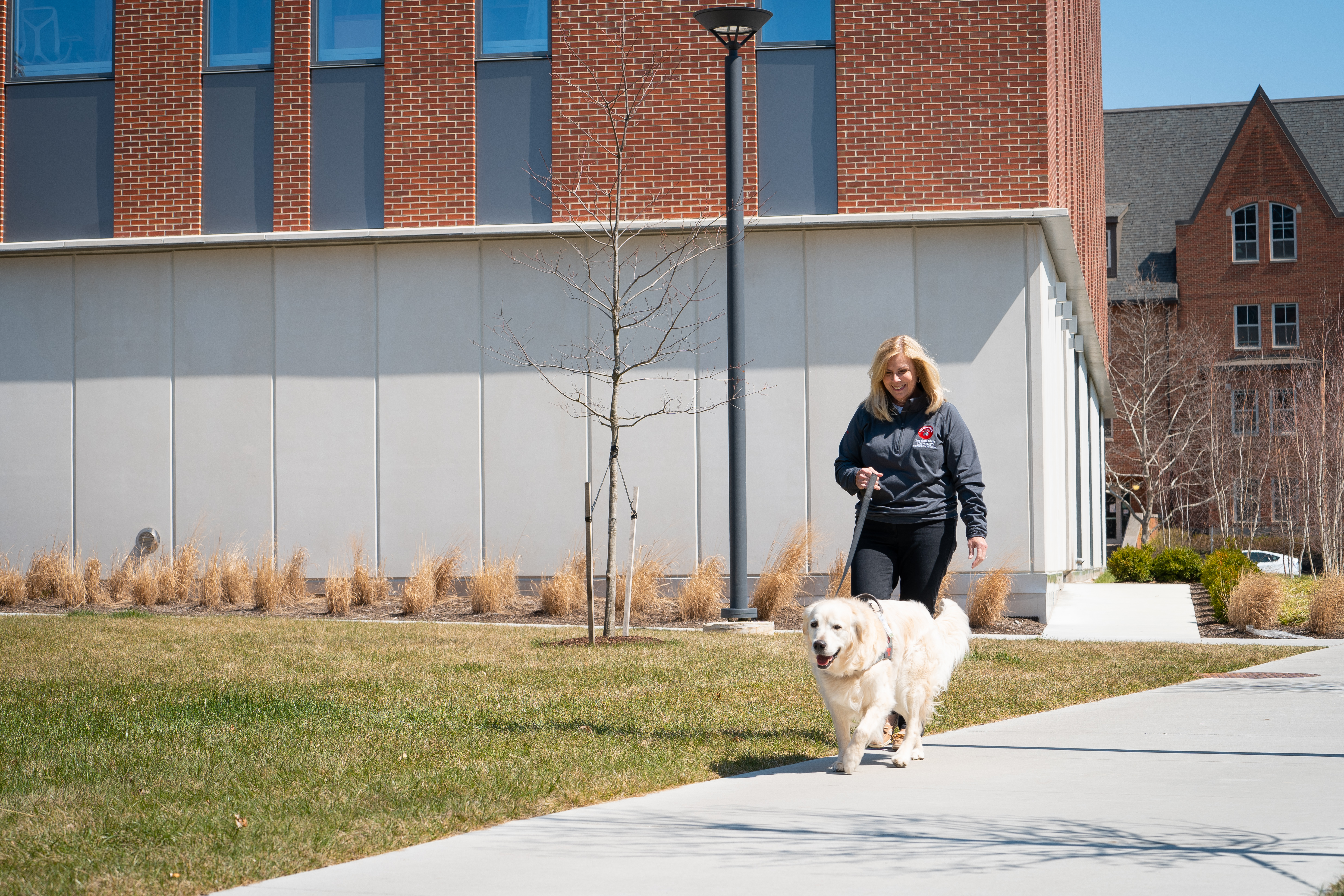 Beth Steinberg walking a dog beside Heminger Hall