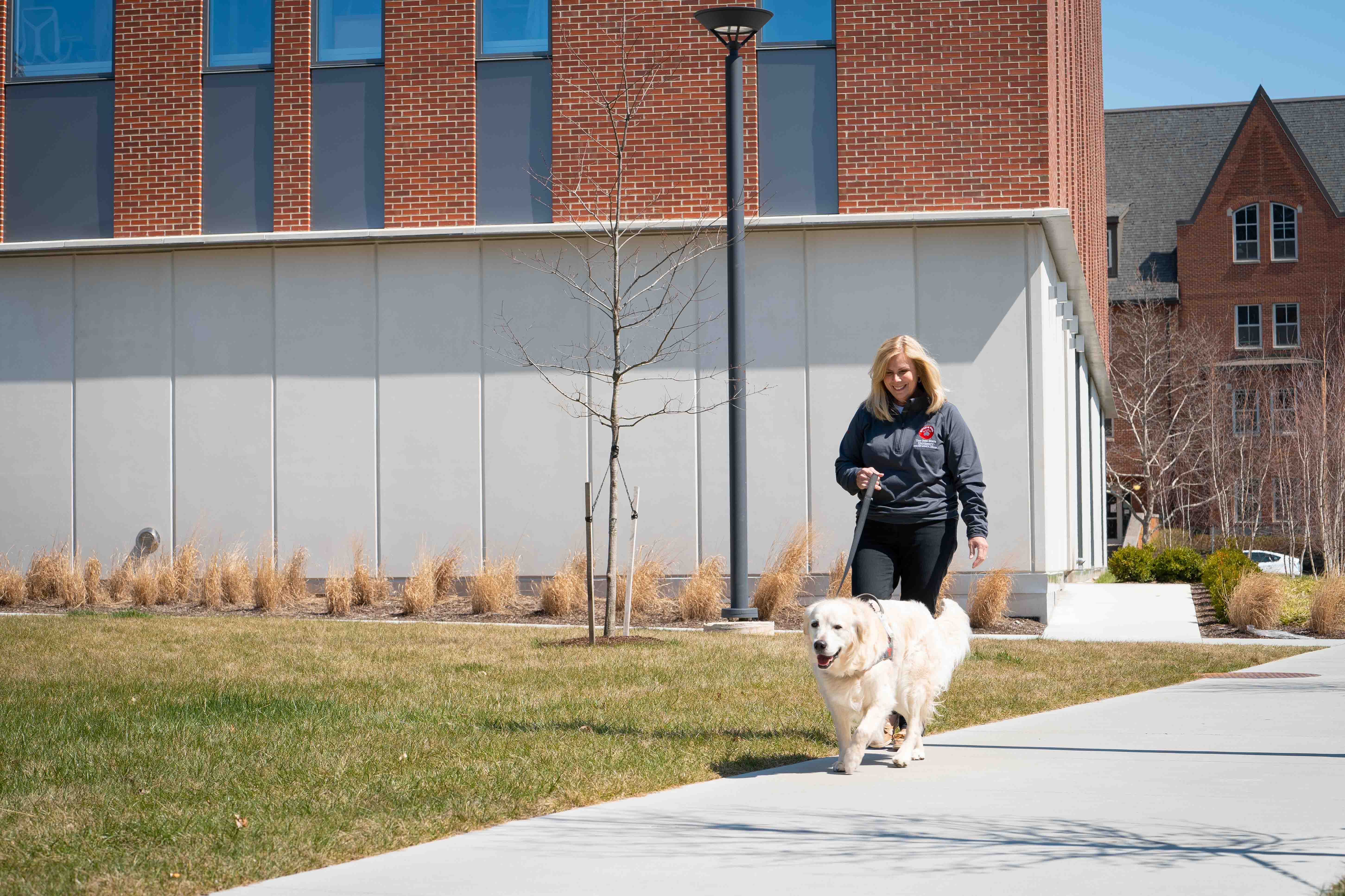Beth walking a Buckeye Paws dog outside of Heminger Hall