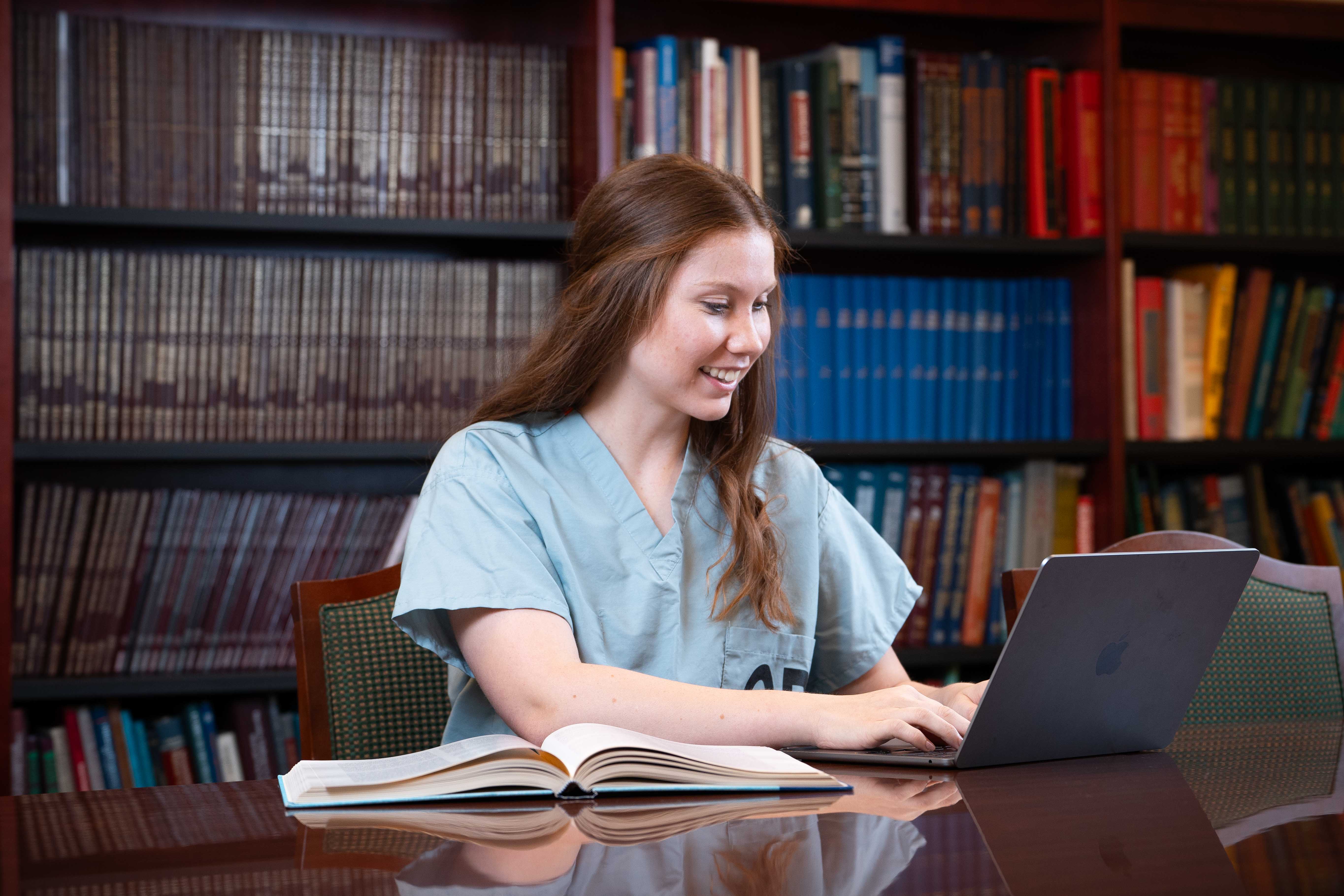 Emily Rice working on her laptop in a library