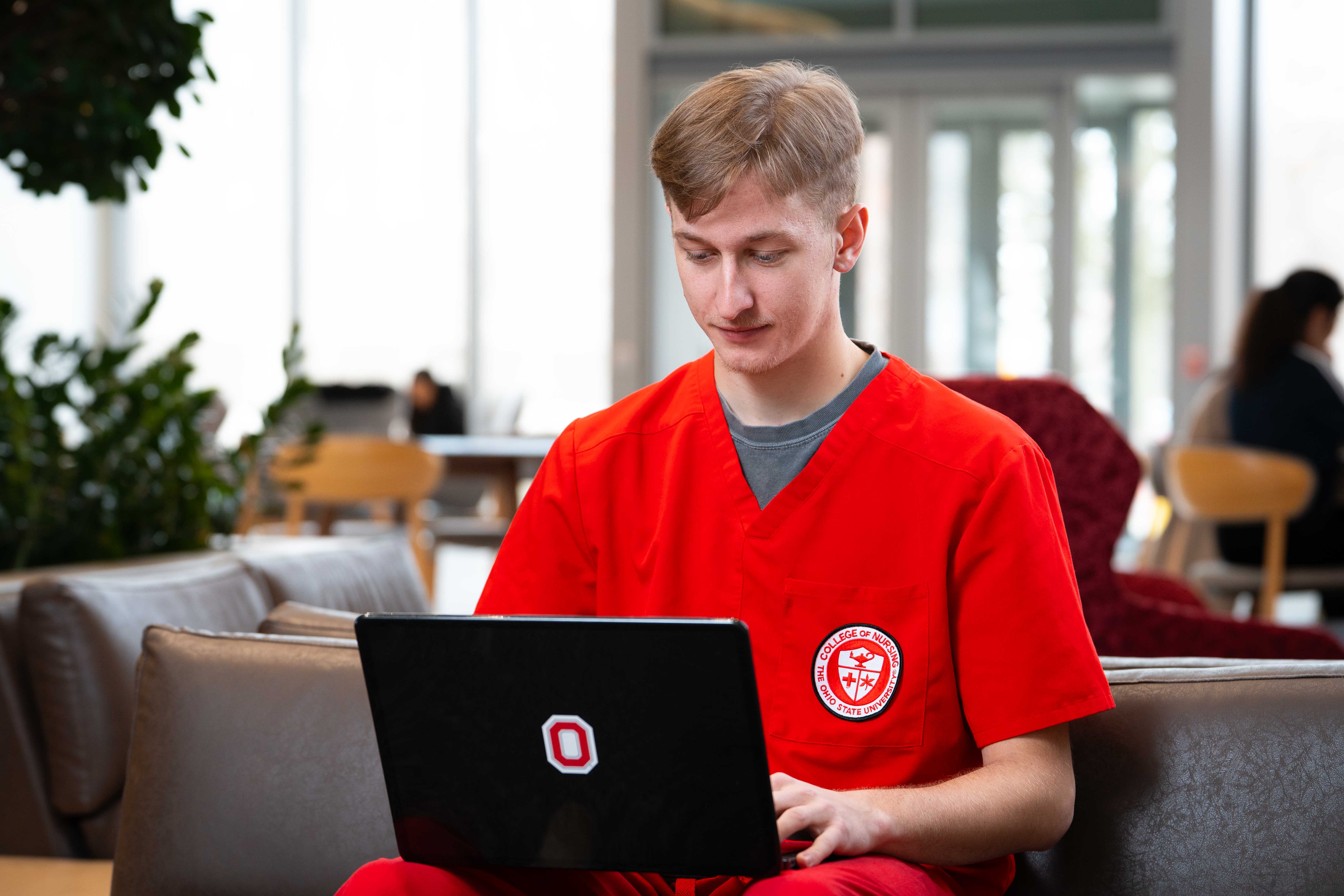Cole Sullivan studying on his laptop in the atrium of Heminger Hall.