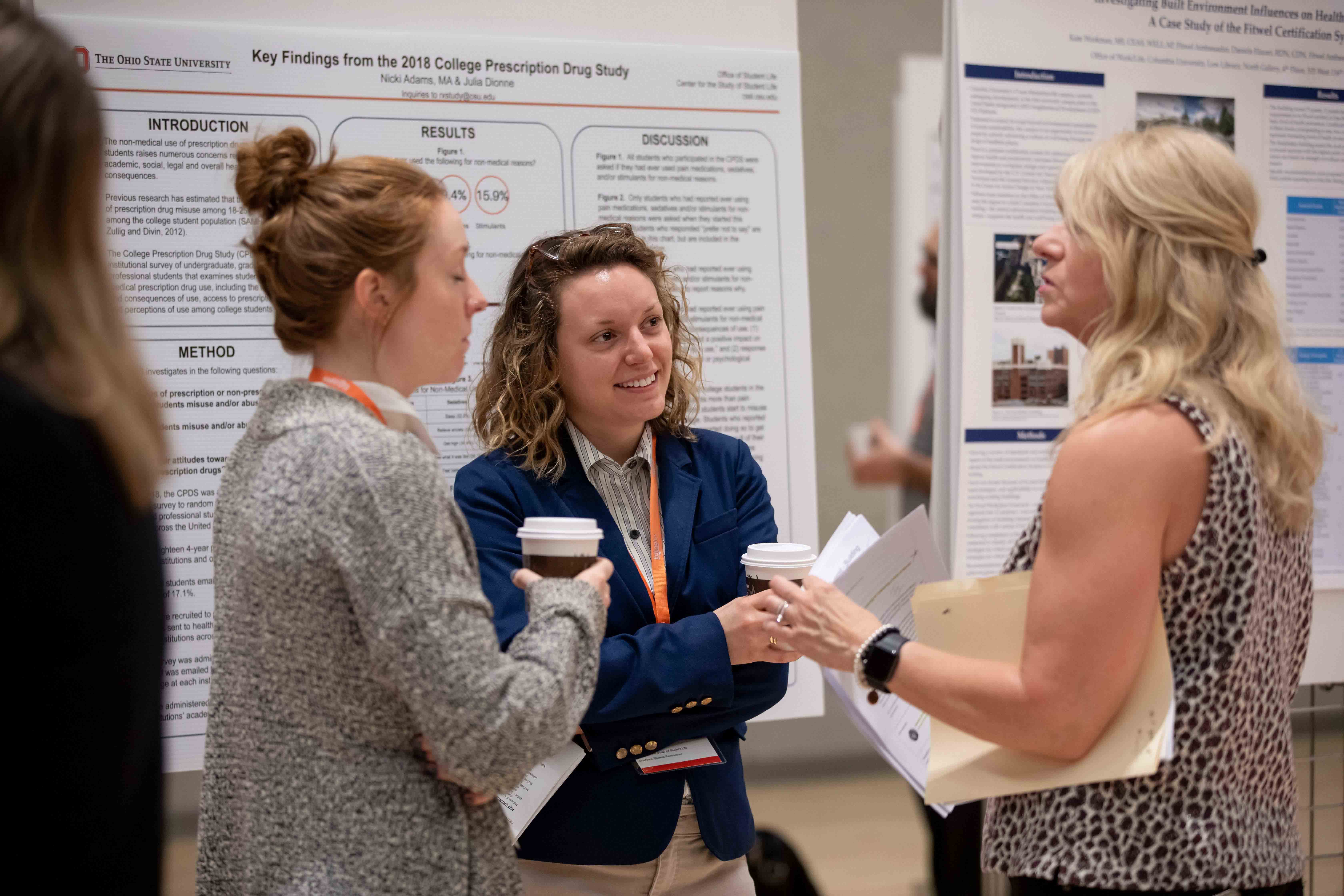 A group of three women talking in front of research presentations