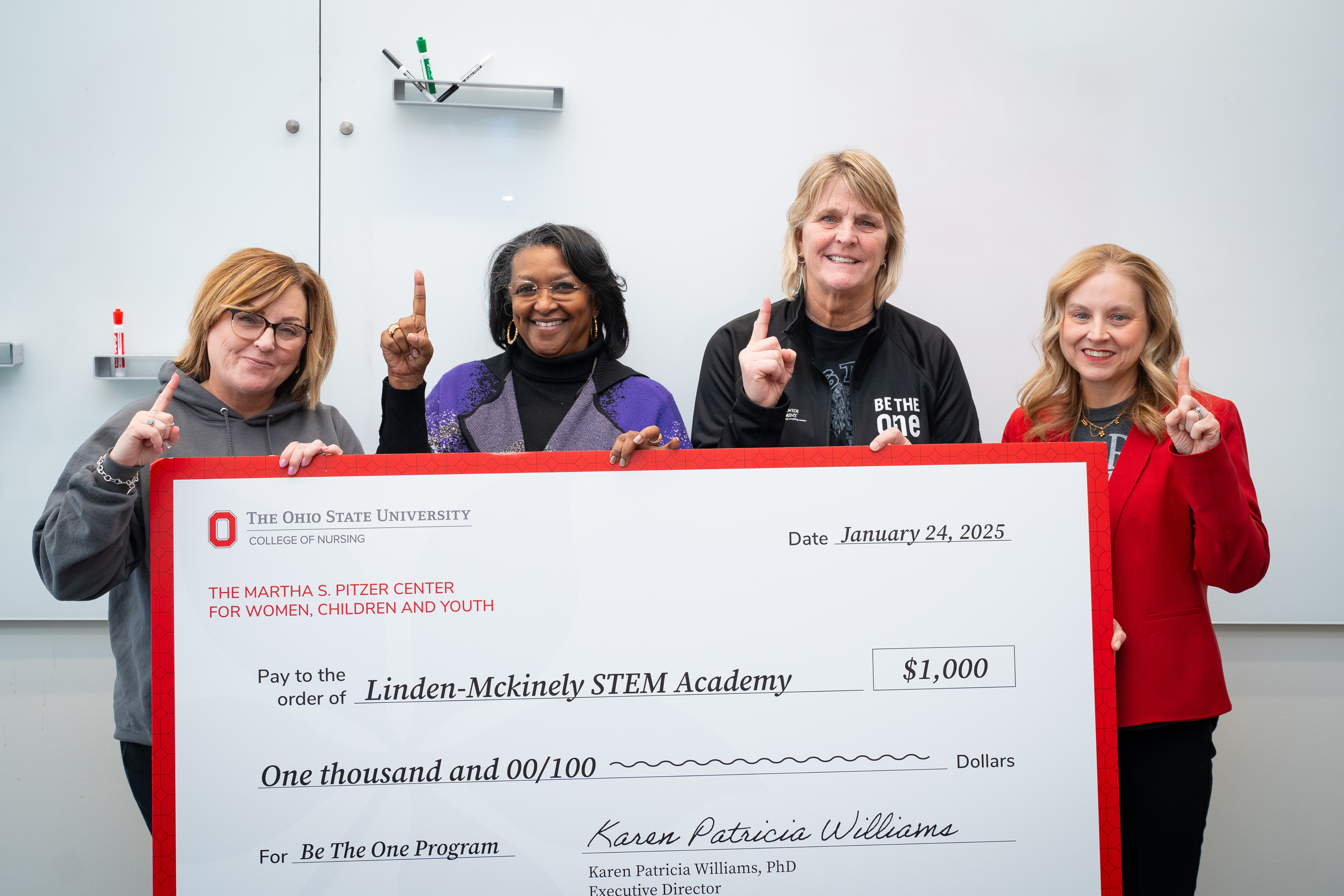 Carla Hegyi, Karen Patricia Williams, Dawn Heideman and Chris Fortney with the Martha S. Pitzer Center’s donation to the Be the One program. Their fingers are raised in the Be the One salute.