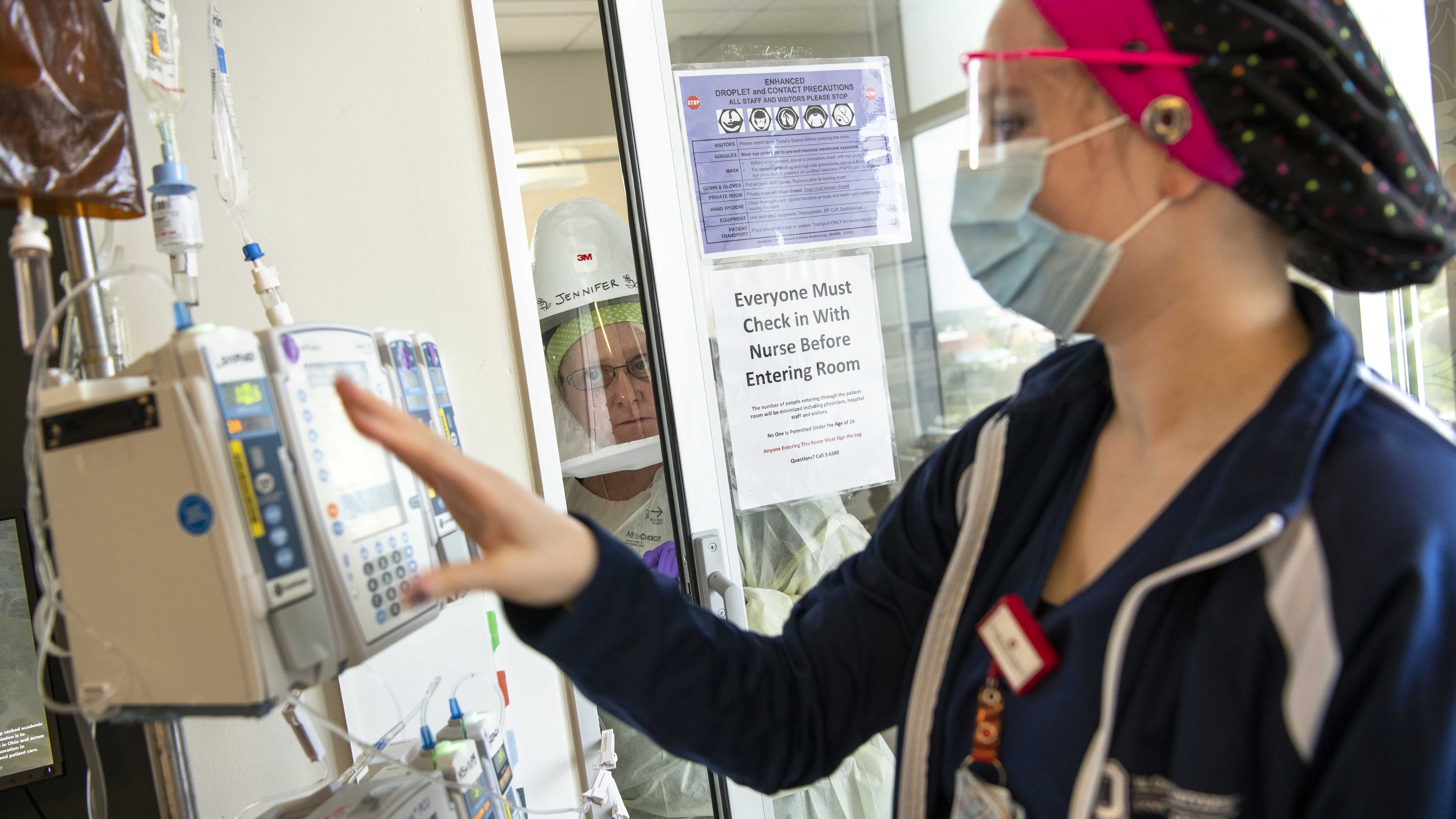 Nurses at OSUWMC using the system. Jennifer Ogden in full PPE; Morgan Drouillard outside the patient's room.