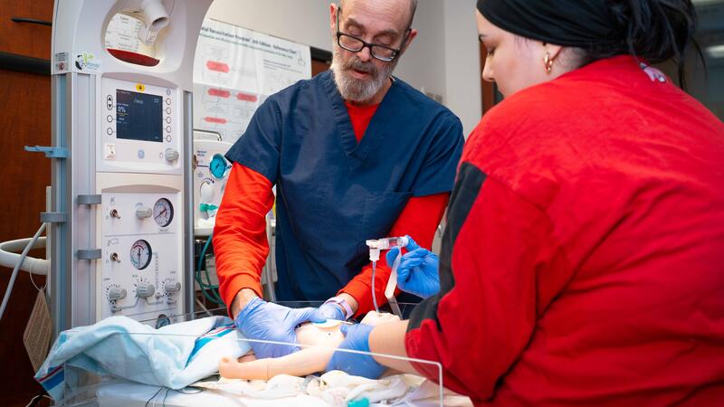students practice on a nursing simulation baby