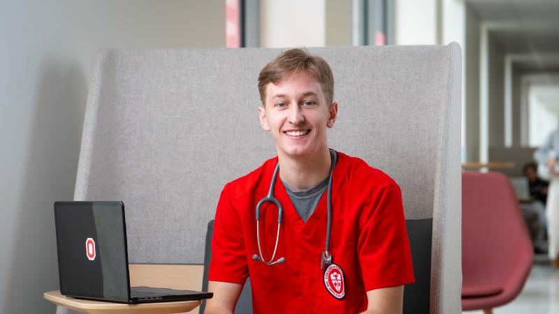 Cole Sullivan smiling in red scrubs