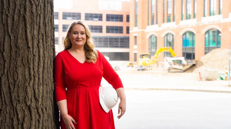 Olivia Cotton on construction site holding hard hat