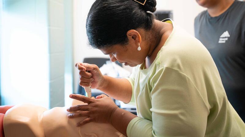 student works on mannequin patient during lab