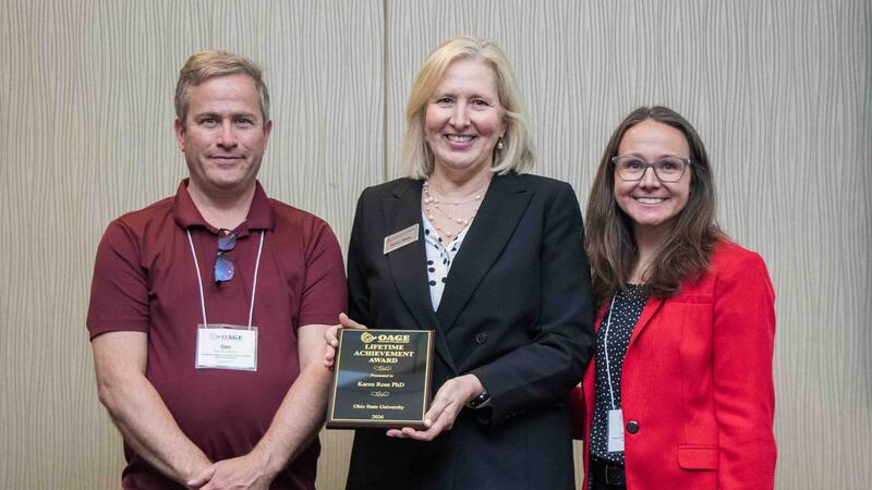 Dean Rose holds and displays her award plaque