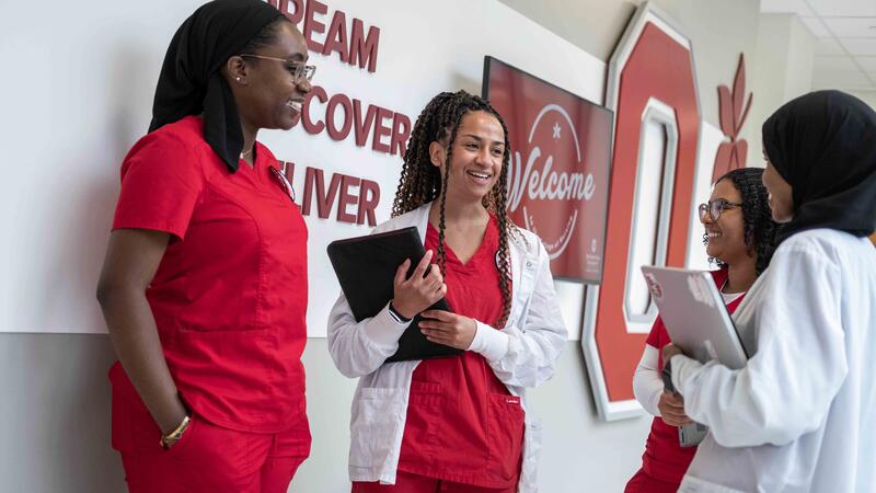 BSN students in red scrubs talking in Heminger Hall