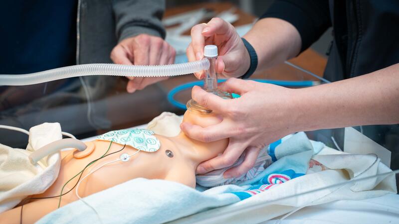 student holding breathing device over neonatal dummy