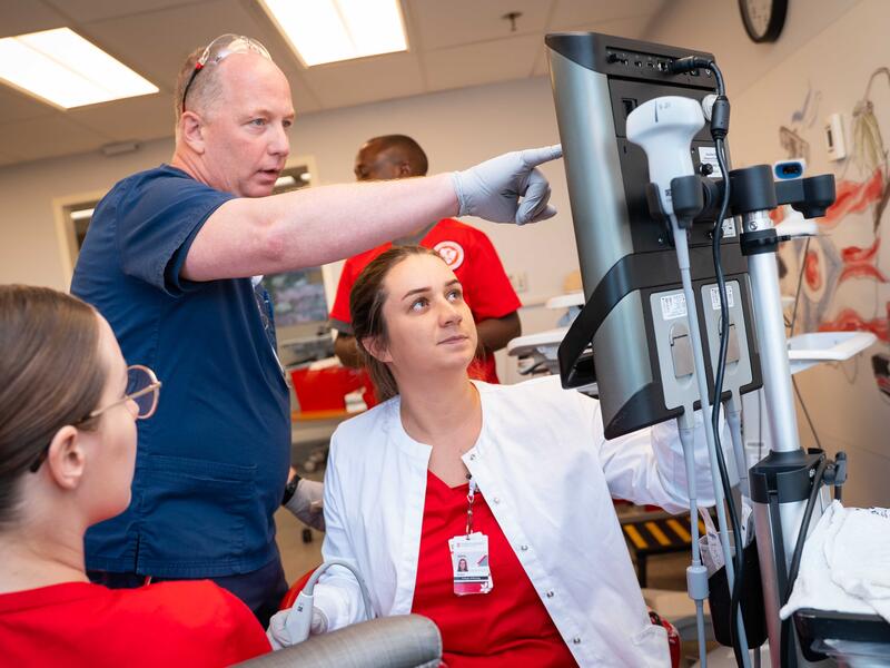 clinical instructor with nursing students points to monitor