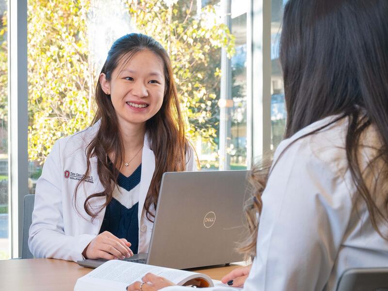 Students in white coats working on computer