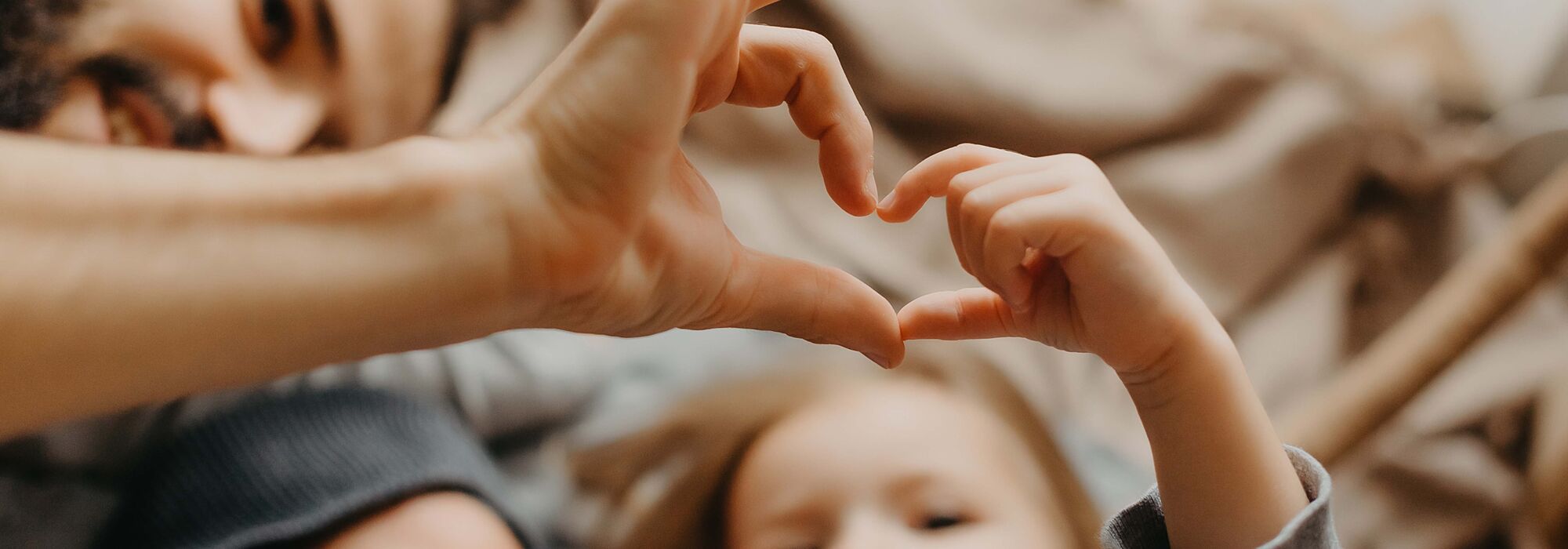 Young girl and father creating a heart with their hands together