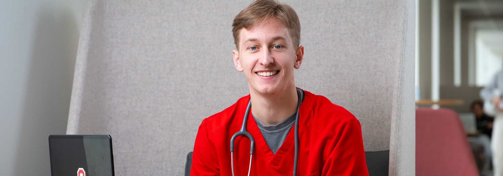 Cole Sullivan smiling in red scrubs