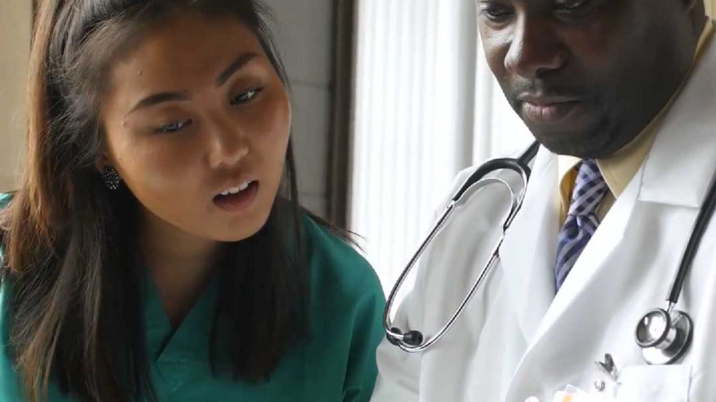 Doctor showing nurse information on computer