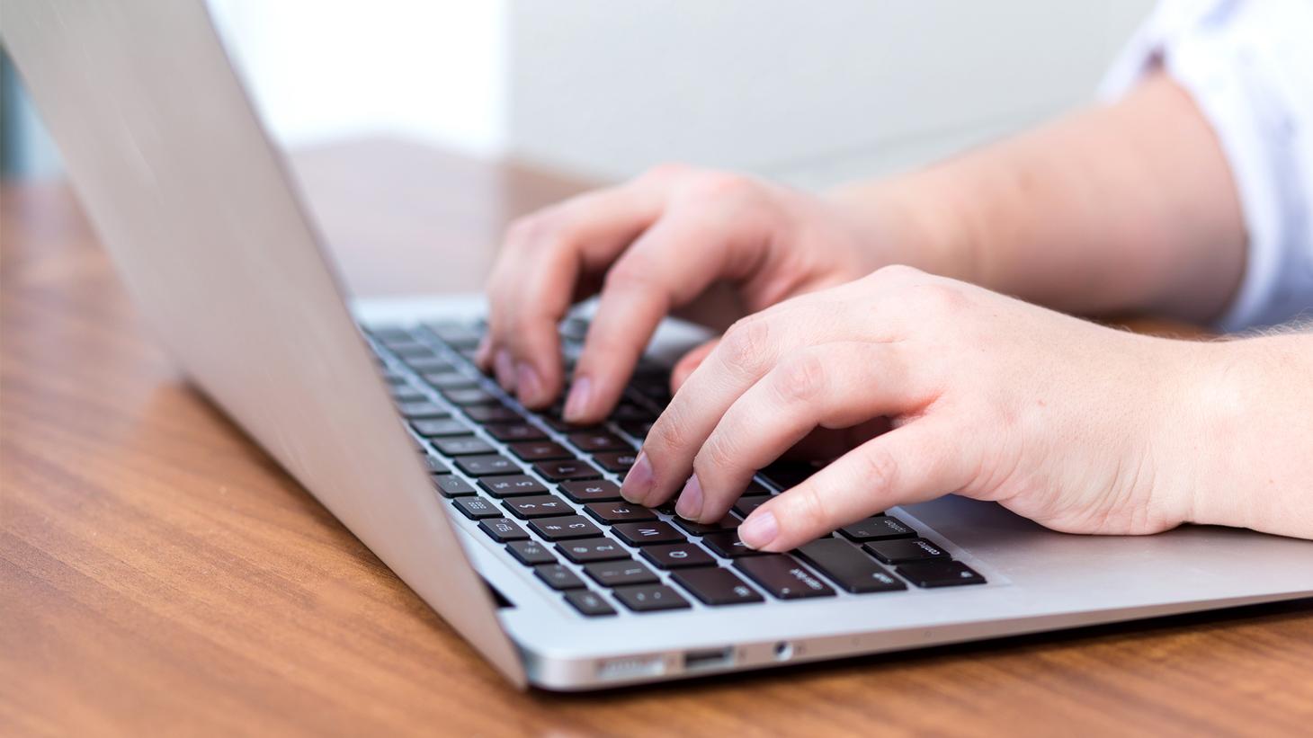 Close-up of hands typing on a laptop