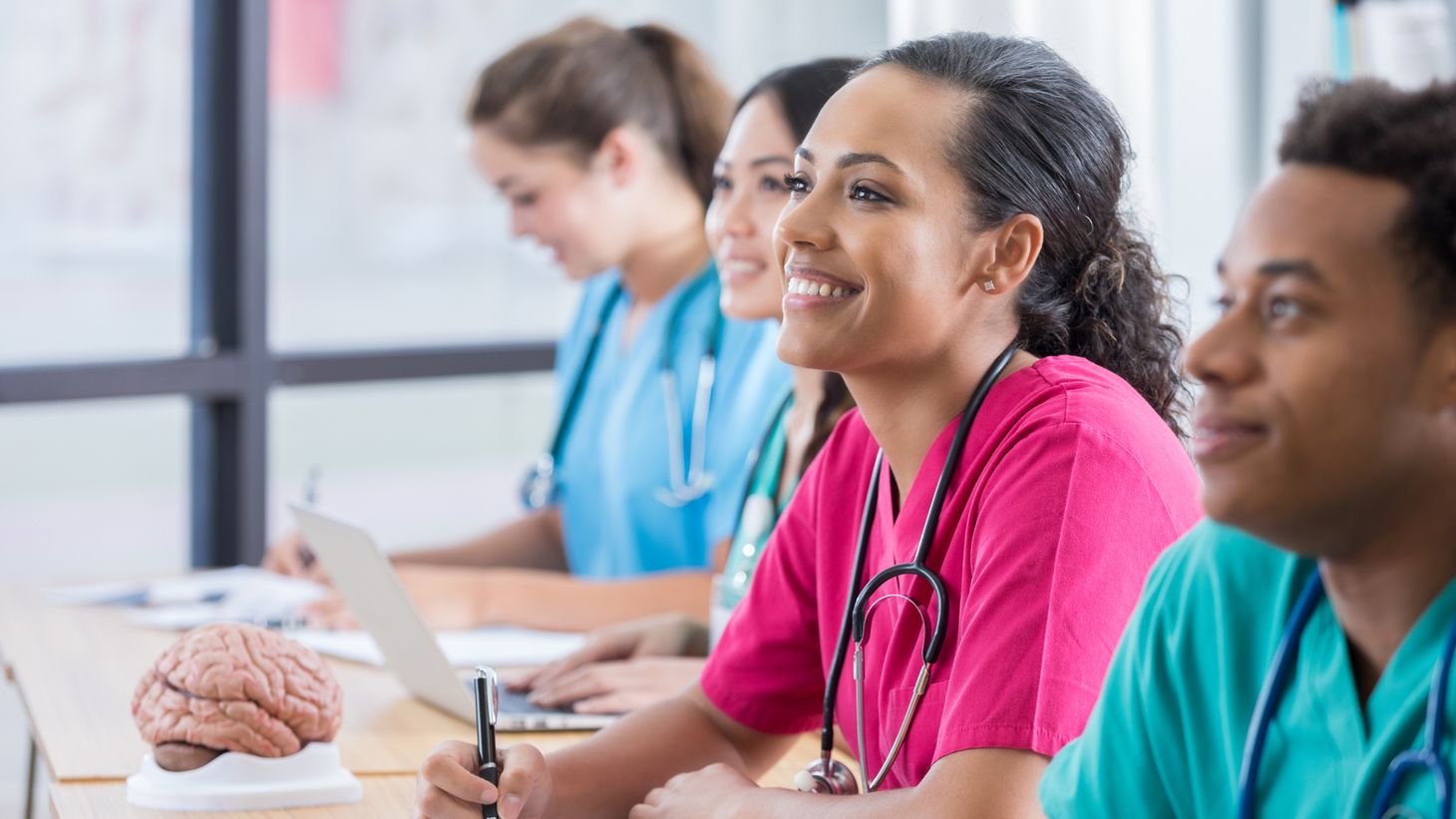 Female nurse sitting at desk smiling.