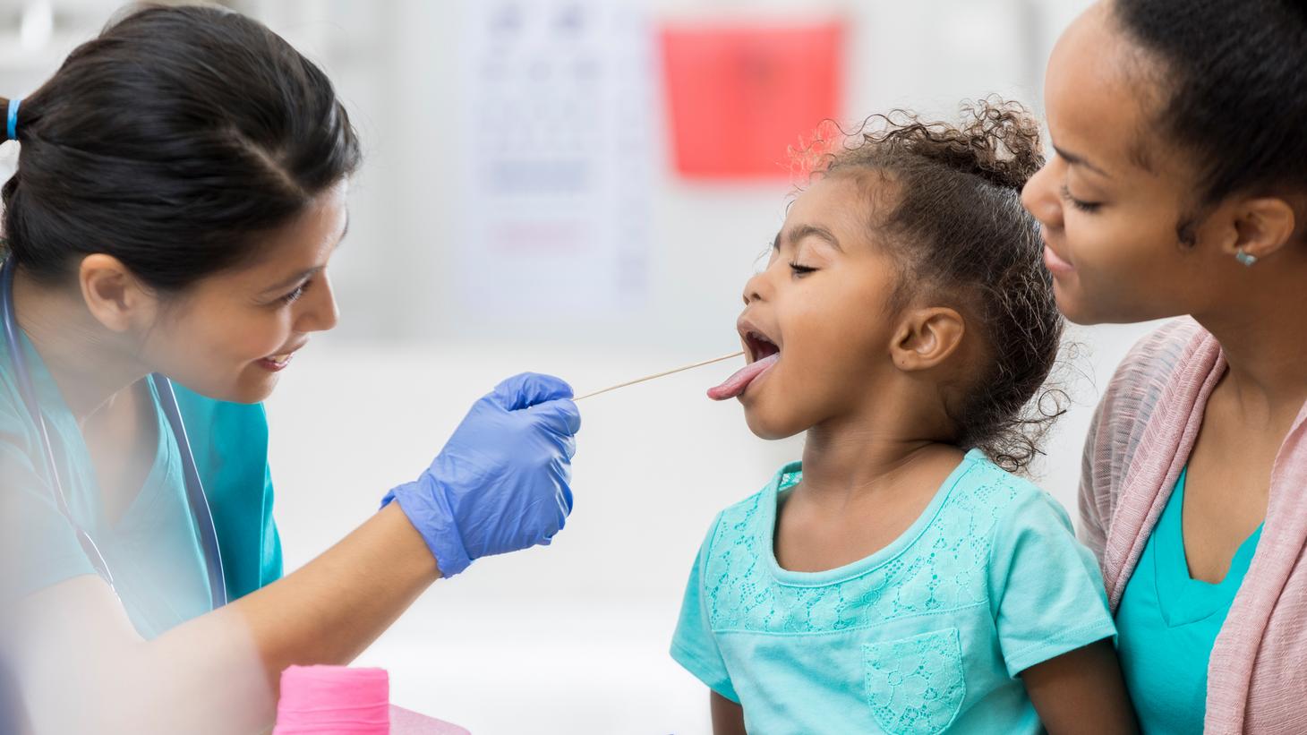 Nurse looking inside a child's mouth.