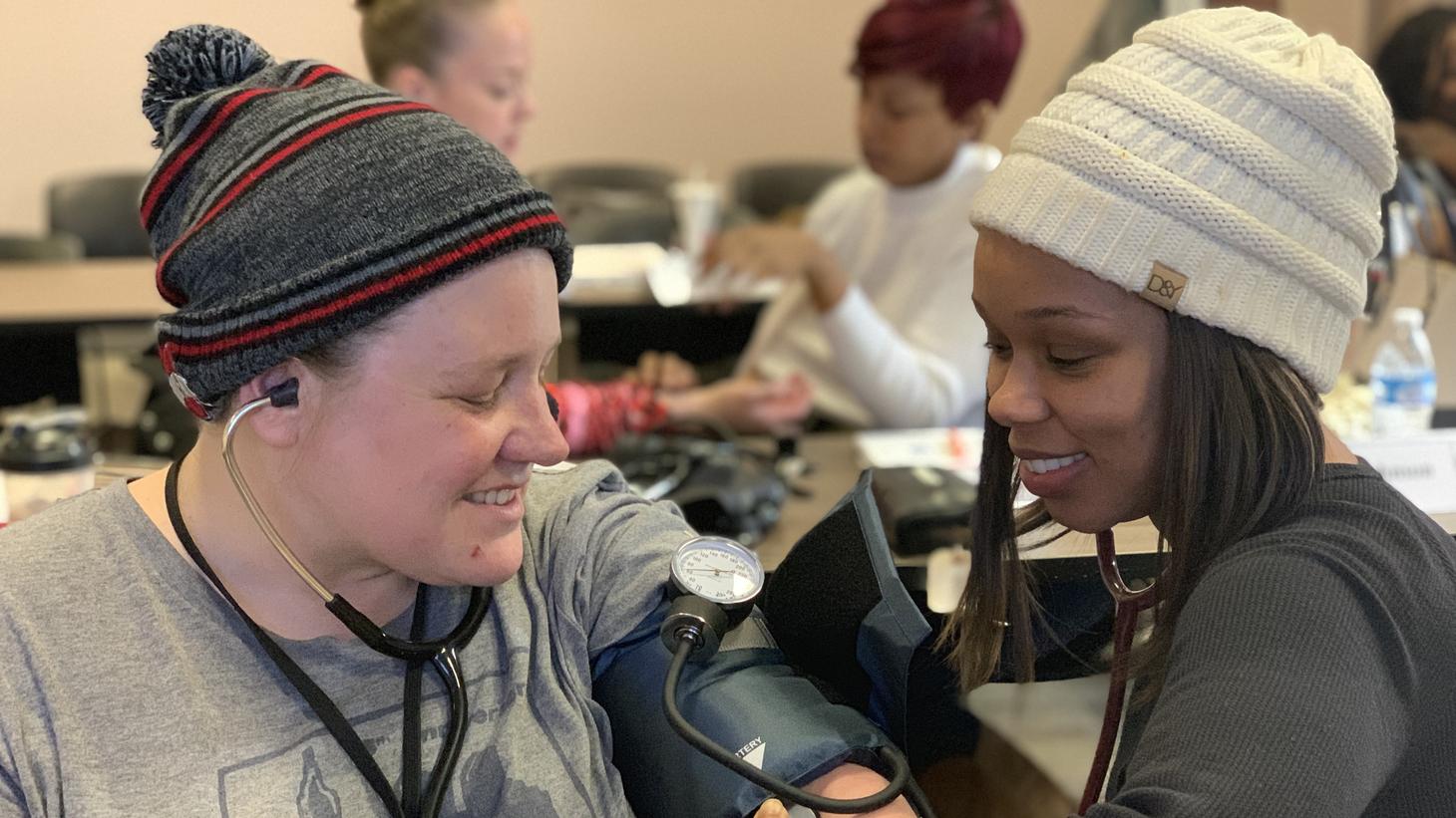 Community Health Workers training each other to take blood pressure reading