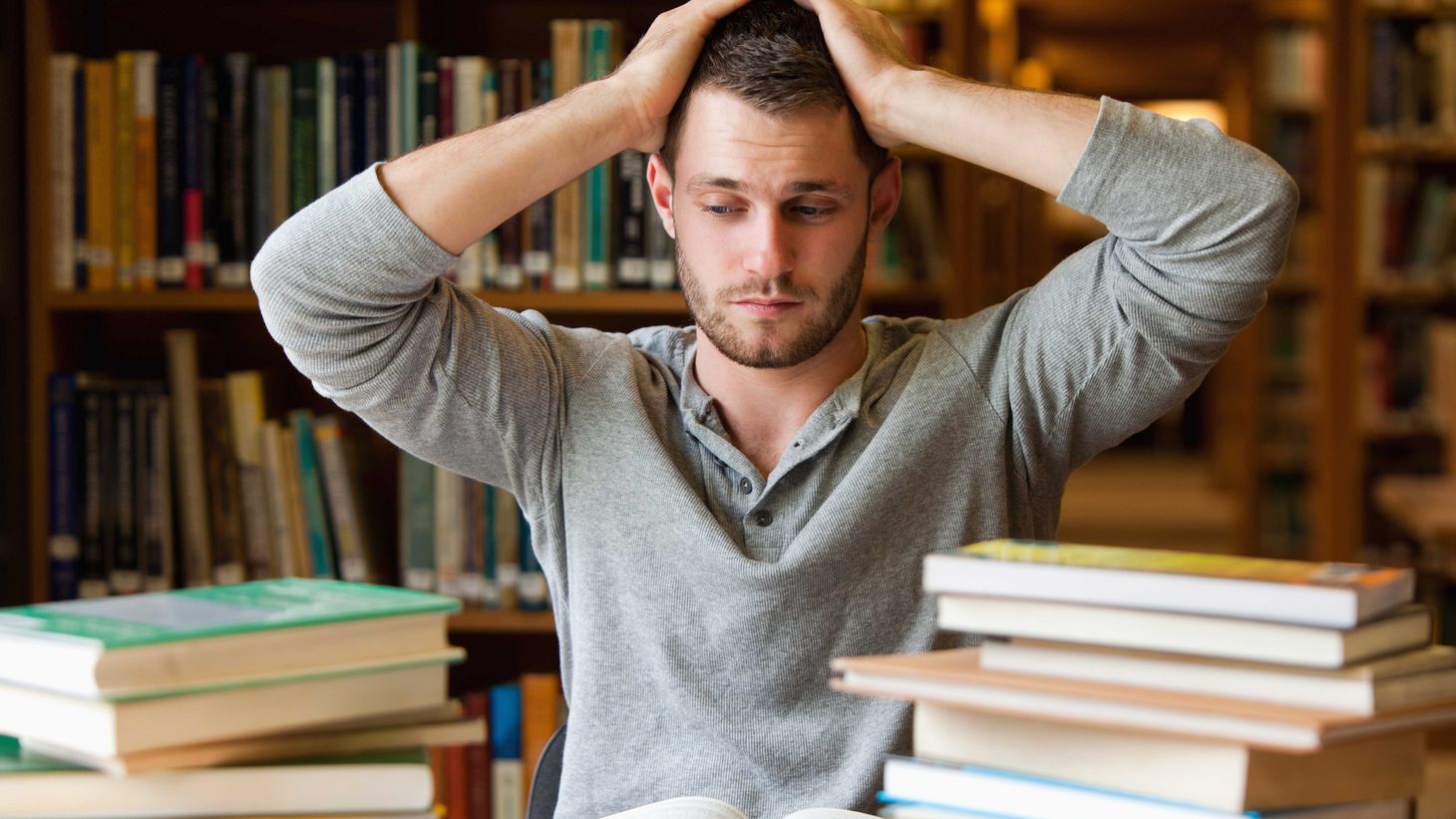 young man with hands on head looking anxious