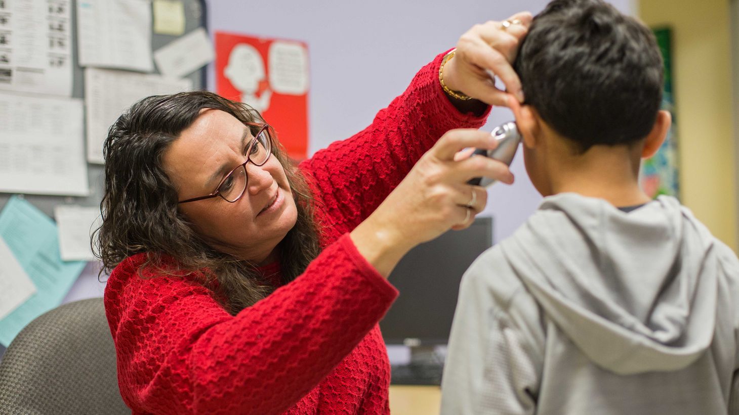 school nurse checking the ear of a young boy