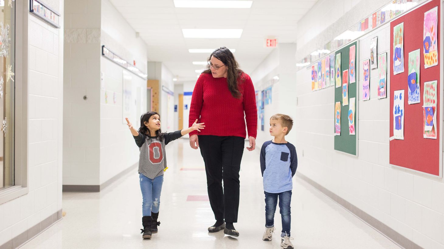 school nurse walking down hallway with two young students