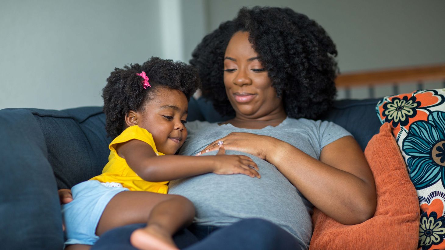 woman and daughter touching pregnant belly