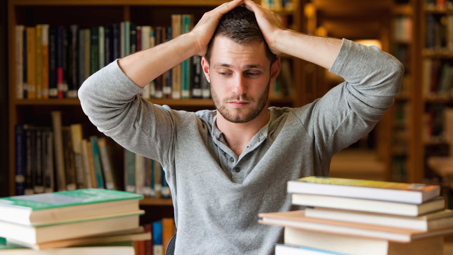 young man with hands on head looking anxious