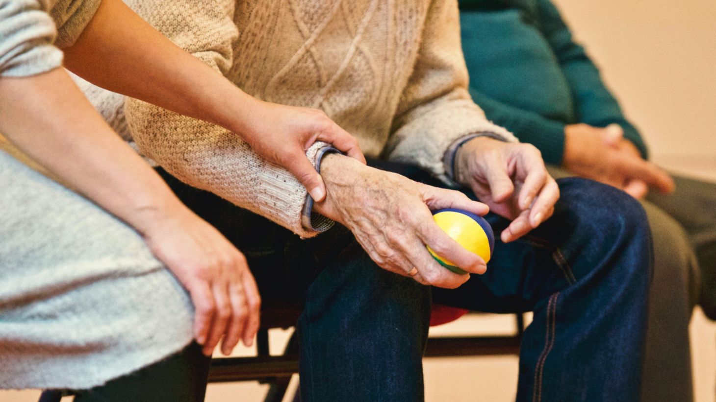 young woman resting her hand on an elderly man's arm while he holds a ball