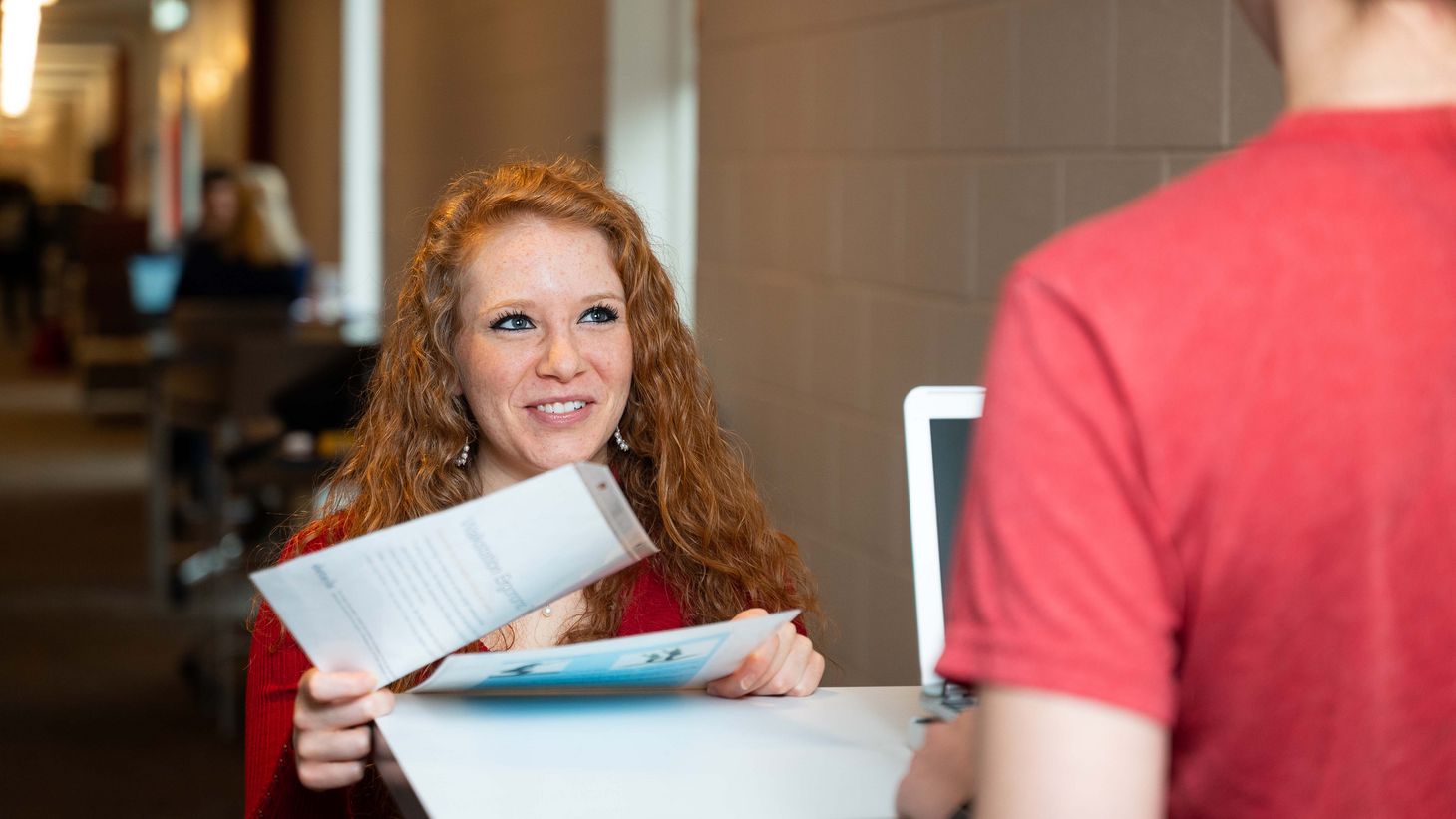 two students conversing and one student passing a note to another