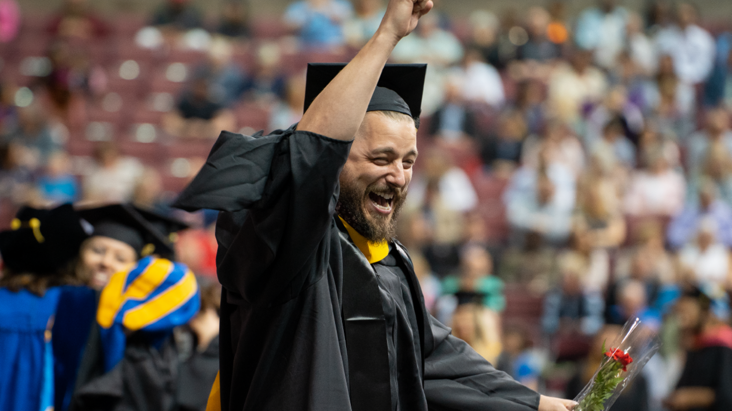 man in cap and gown attire with fist in the air. 