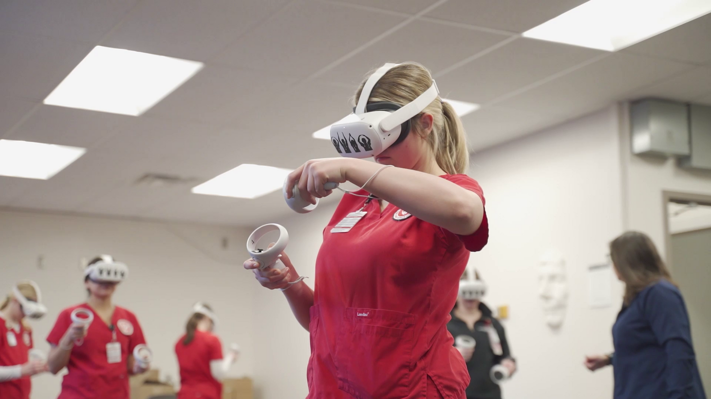 nursing student in red scrubs using virtual reality headset