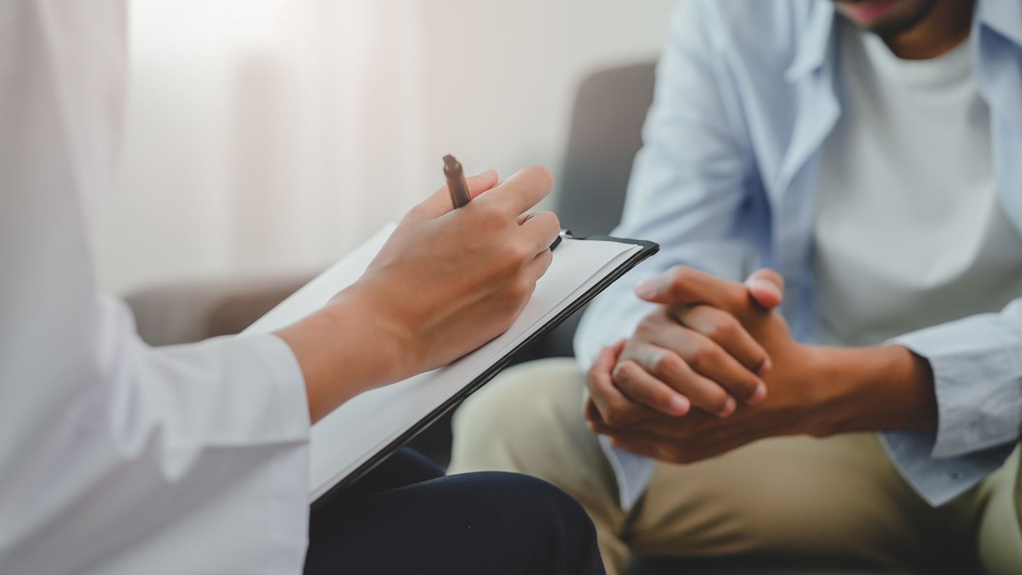 clinician taking notes during meeting with patient