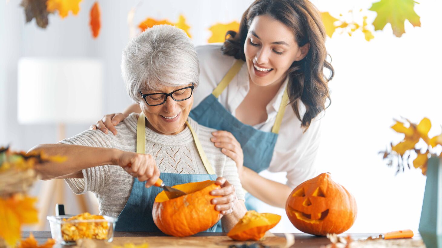 Middle-aged woman and senior woman carving pumpkins