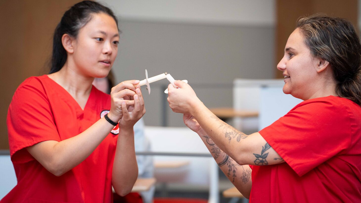 Two nursing students in red scrub light their candles