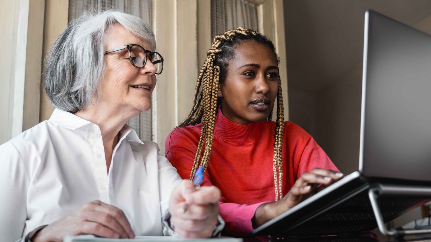 young woman helping older woman use a computer