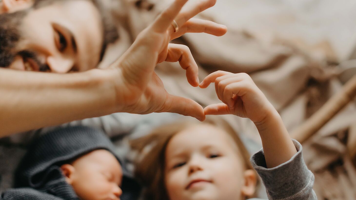 Young girl and father creating a heart with their hands together