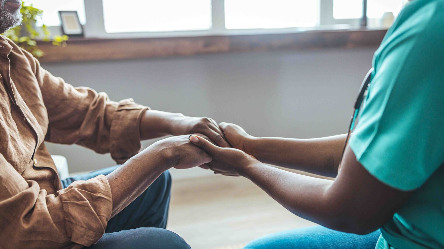 Close-up of home caregiver and senior man holding hands