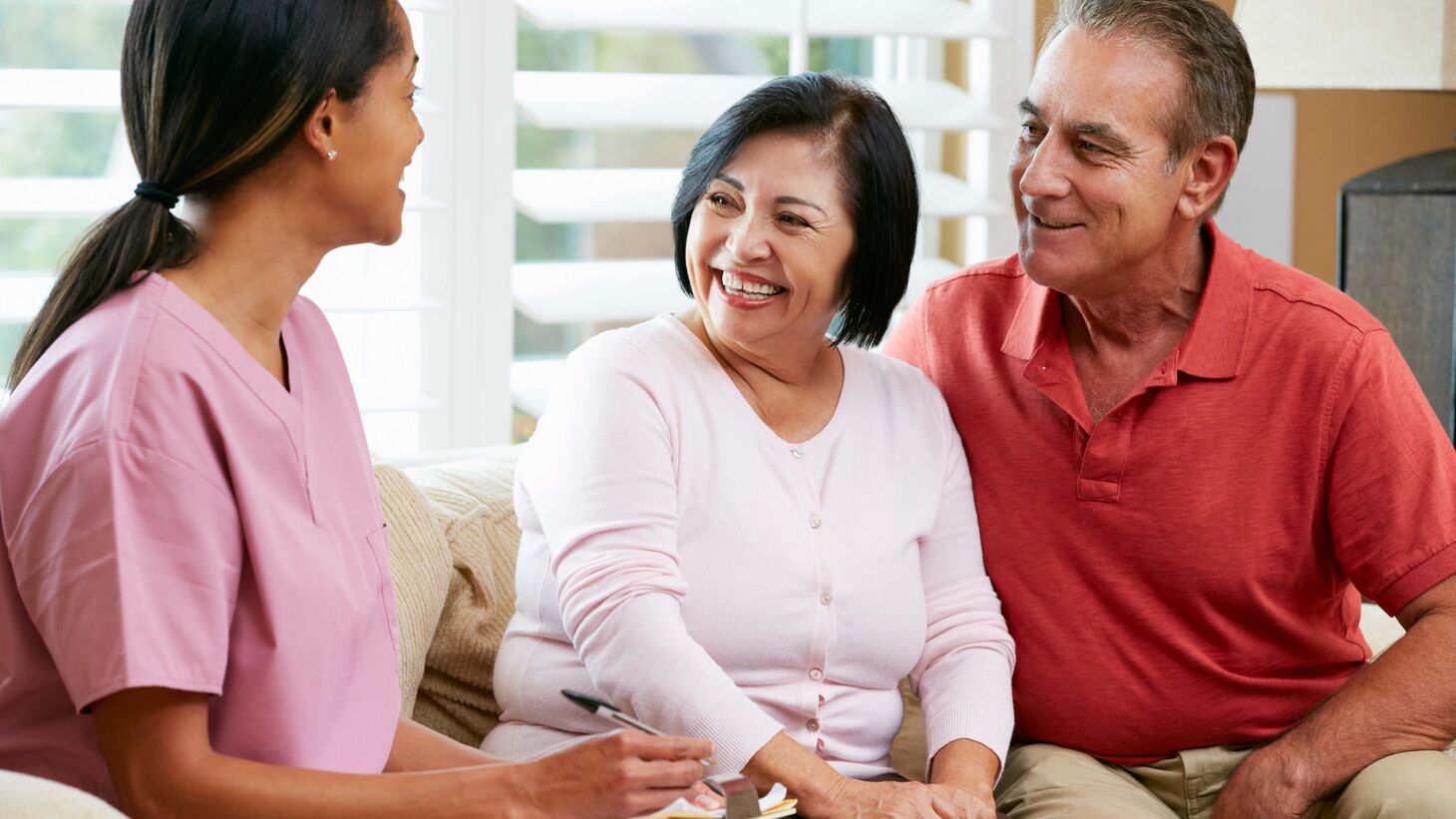 Nurse and elderly couple sitting together talking