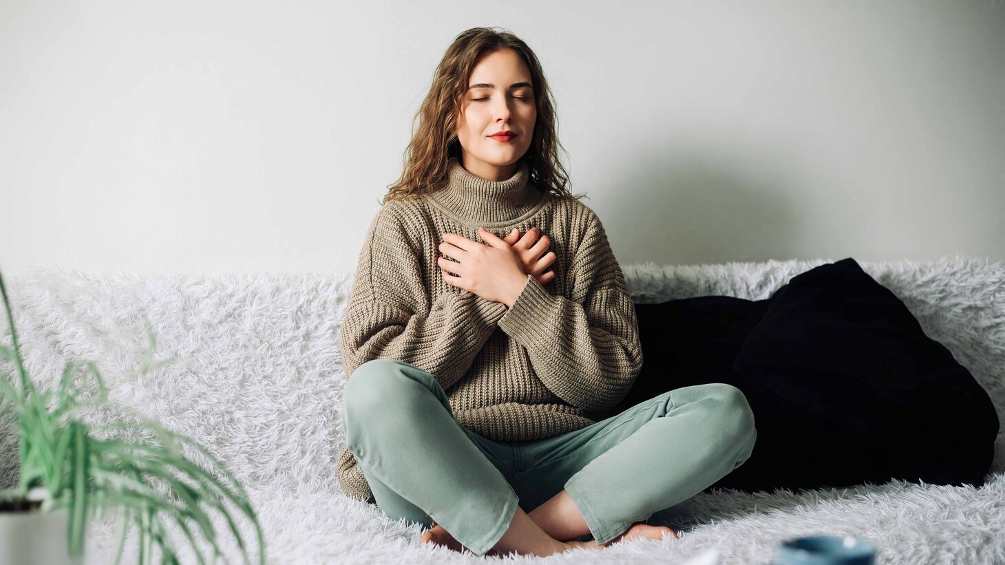 Caucasian woman sitting on couch practicing deep breathing