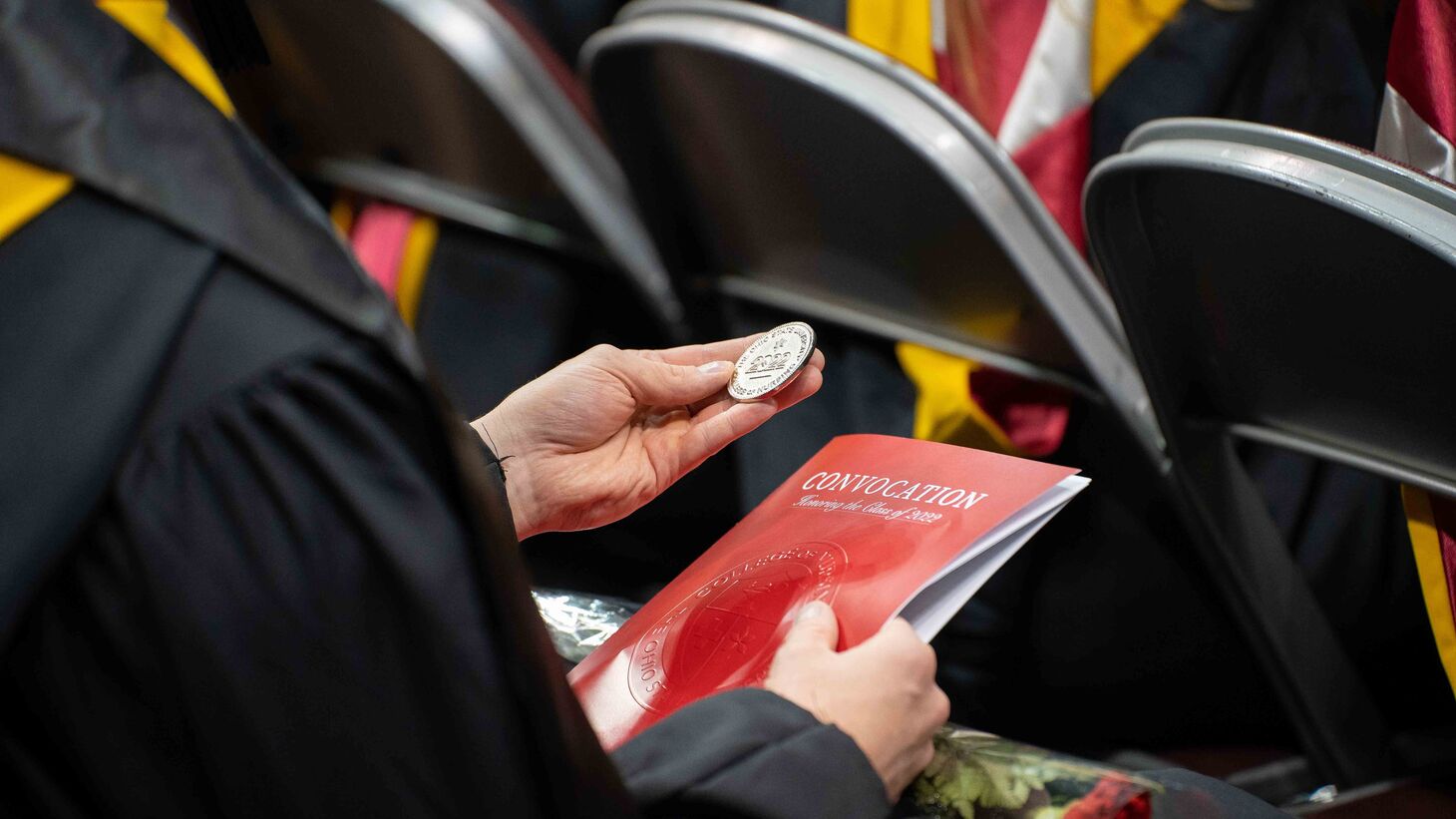graduating student holding Convocation program and challenge coin